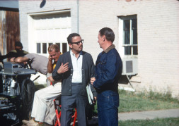 Production crew member conversing with actor George Mitchell (Jake Kiner) dressed in blue denim jacket and jeans, in downtown Ft. Scott, Kansas.