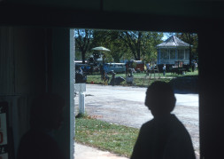 Silouette of a woman in a doorway looking out on the production crew preparing to film in a local park located in Fort Scott, Kansas.