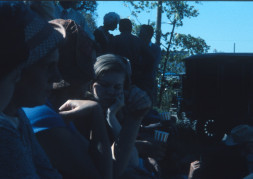 Actors and crew in shadow watching the filming of a scene.