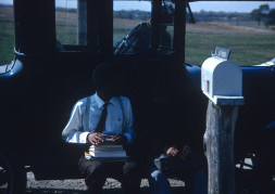 Actor Kyle Johnson (Newt Winger) and another actor (obscured) sitting on black antique car.