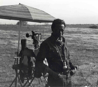 Director Gordon Parks smoking a pipe next to a video camera.