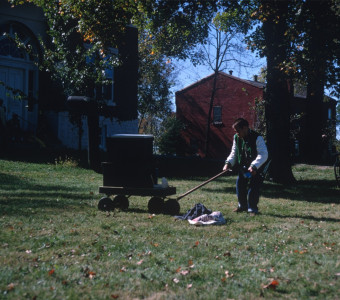 Production crew member outside of the courthouse from the trial scene moves something with a wagon.