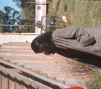 Actress Carol Lamond (Big Mabel) in wool coat by wooden stairs in downtown Fort Scott.
