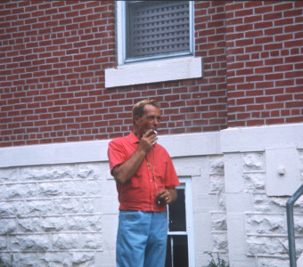 Crew member smoking a cigarette next to the courthouse building.