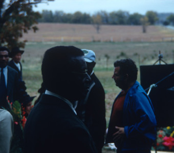 Actor Joel Flullen (Uncle Rob), wearing glasses, and other actors and production crew filming Sarah Winger‚Äôs funeral scene.