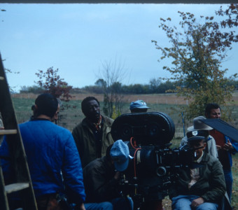 Director Gordon Parks, behind camera in green jacket, and production crew filming in rural area outside of Fort Scott, Kansas.
