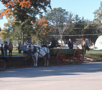 Wagon and horses waiting on the side of a street in downtown Fort Scott with crew members behind it.