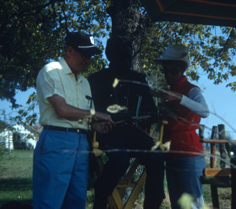 Production crew and Director Gordon Parks (obscured) discussing a document outside of Winger home set.