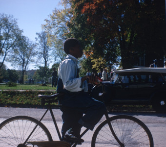 Actor riding a bike in the street by courthouse.