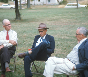 Three older Actors dressed formally seated.