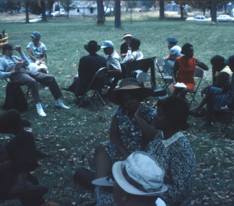 Cast and crew members seated in chairs on lawn; one actor holds The Learning Tree book
