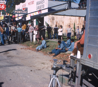 Cast and crew, including Kyle Johnson (Newt Winger), Stephen Perry (Jappy), Carter Vinnegar (Seansy), and Bobby Goss (Skunk) in blue jumpsuits and seated, left, filming a scene in downtown Fort Scott, Kansas.