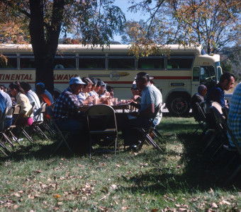 Cast and crew eating a meal in front of production bus.