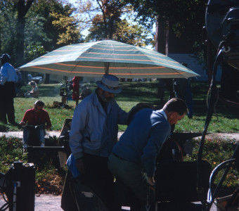 Crew standing underneath an umbrella with production equipment.
