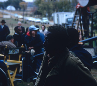 Director Gordon Parks in front with cast and crew members and production equipment behind him.