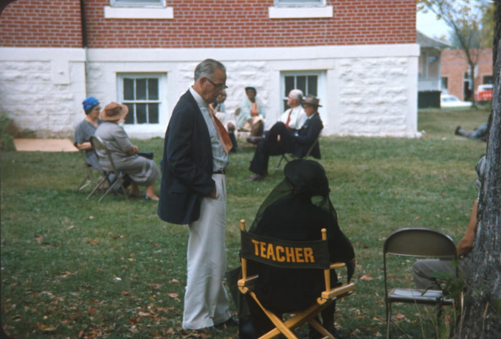 Actress in ‚ÄúTeacher‚Äù chair, likely Hope Summers (Mrs. Kiner), talking to actor and seated with other actors outside of courthouse building used in trial scene.
