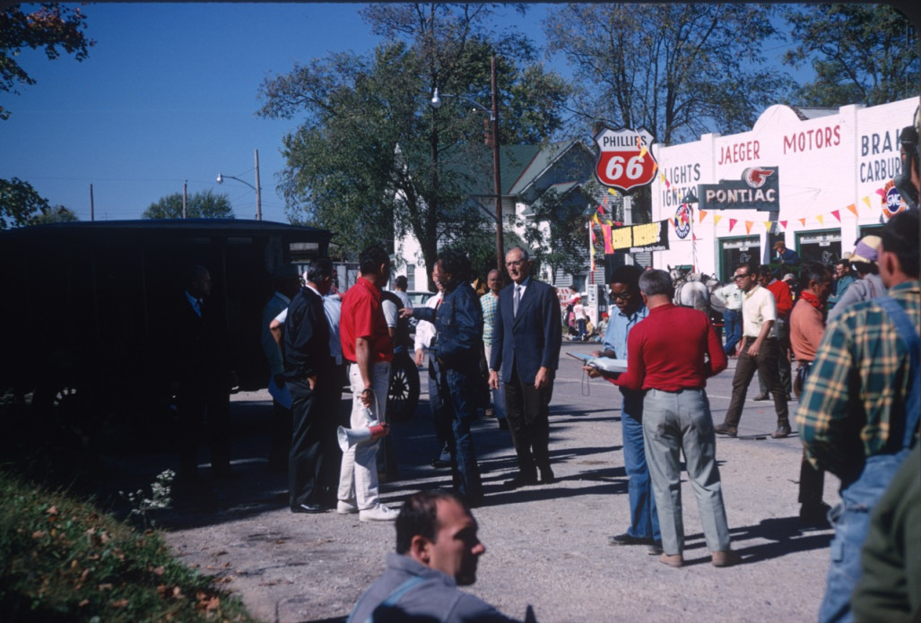 Actors and crew preparing for a scene in downtown Fort Scott, Kansas. Director Gordon Parks (in blue denim) gives instructions, center. Stephen Perry (Jappy), in blue shirt and jeans, consults a book.