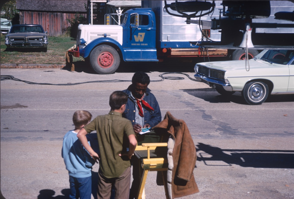 Director Gordon Parks signing autographs for young fans in front of production equipment.