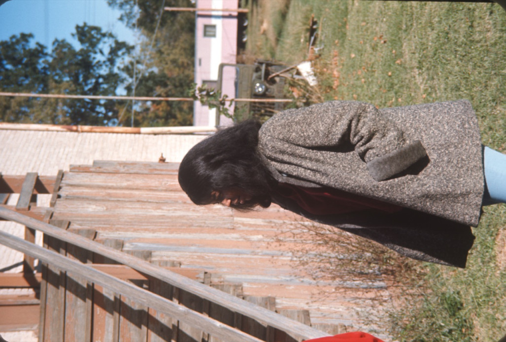 Actress Carol Lamond (Big Mabel) in wool coat by wooden stairs in downtown Fort Scott.