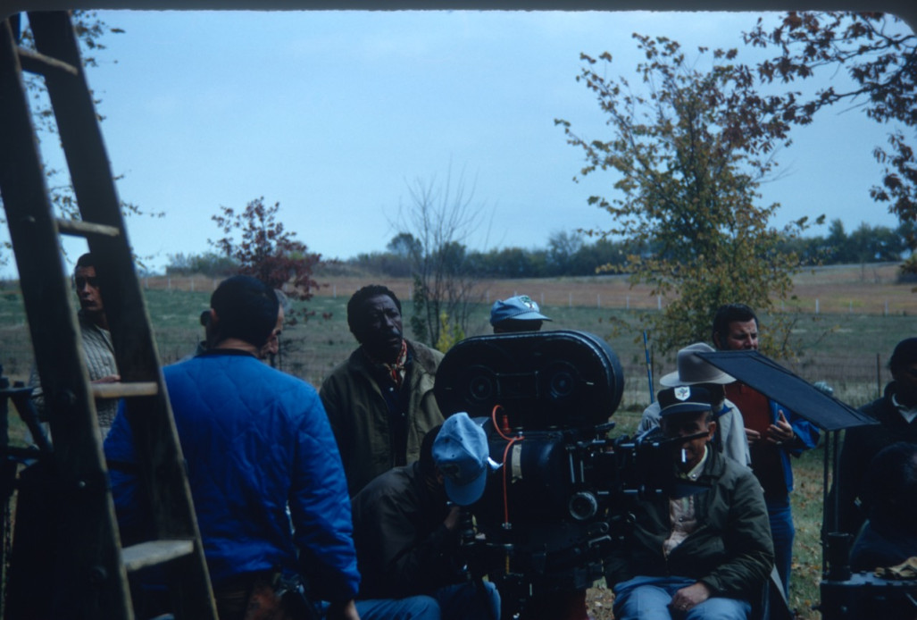Director Gordon Parks and Learning Tree crew filming in rural area Director Gordon Parks, behind camera in green jacket, and production crew filming in rural area outside of Fort Scott, Kansas.
