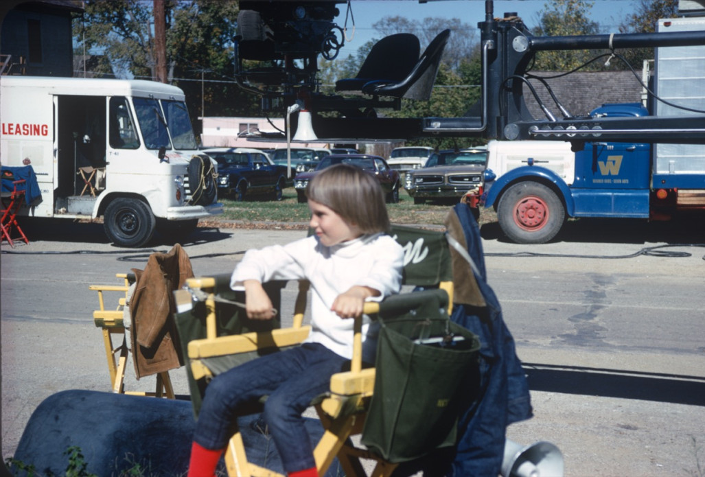 Child sits in Gordon Parks‚Äô director‚Äôs chair amongst film production equipment in downtown Fort Scott, Kansas.