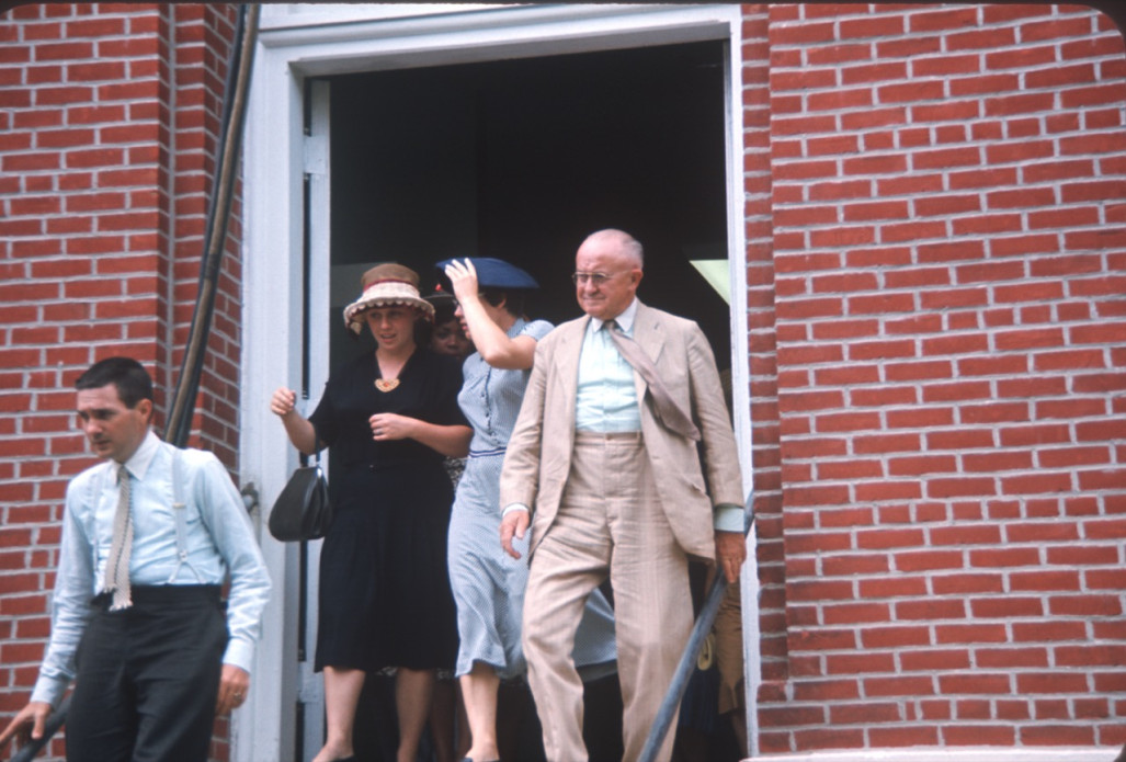 Two Learning Tree actors and actresses in formal dress exiting courthouse Two actors and two actresses exiting courthouse building, in formal attire, likely around filming of trial scene.