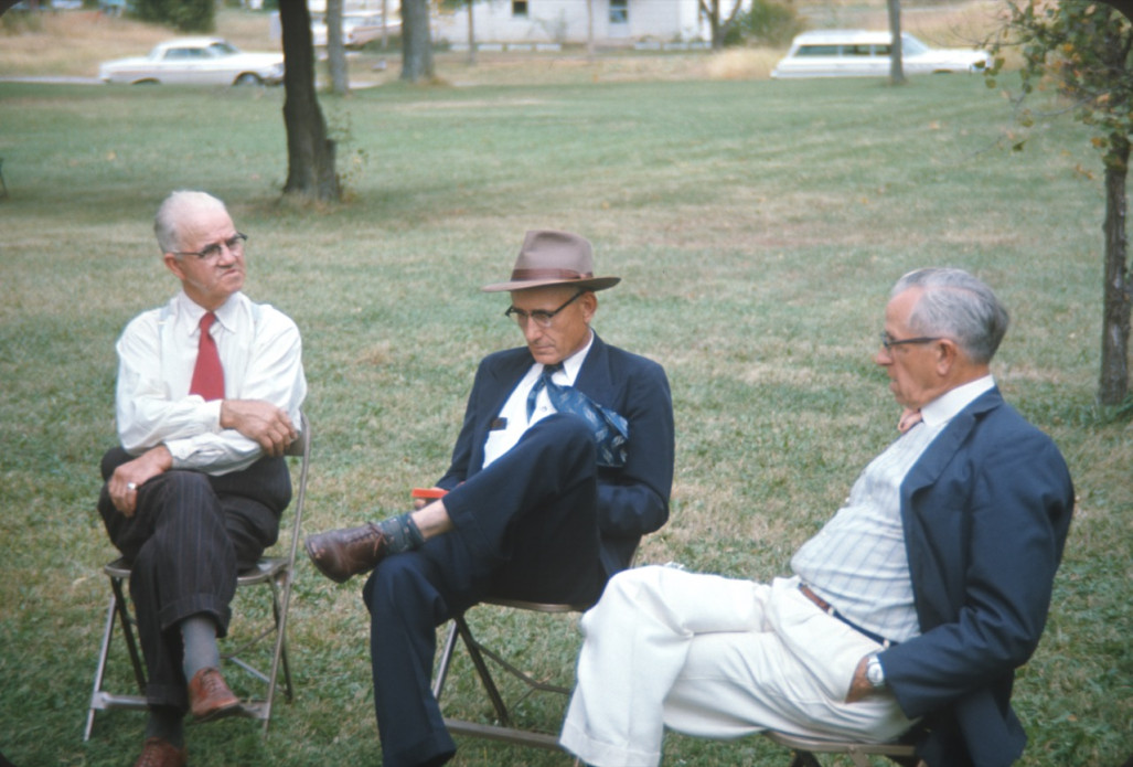 Three elderly Learning Tree actors seated in folding chairs Three older Actors dressed formally seated.