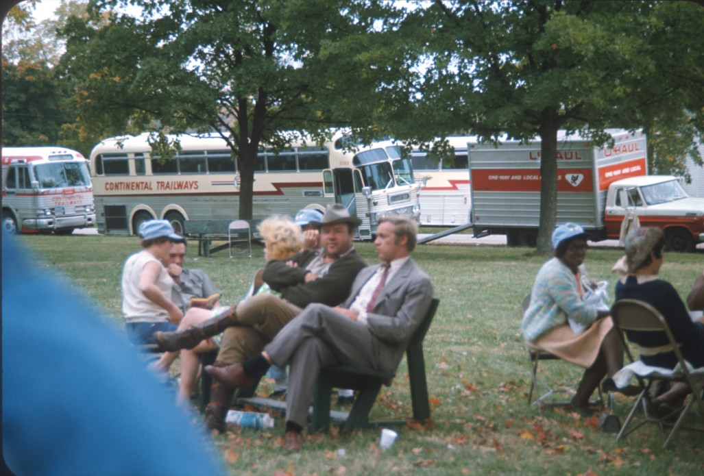 Cast, including Dan Dubbins (Harley Davis) and Dana Elcar (Kirky) seated center, in front of production vehicles.