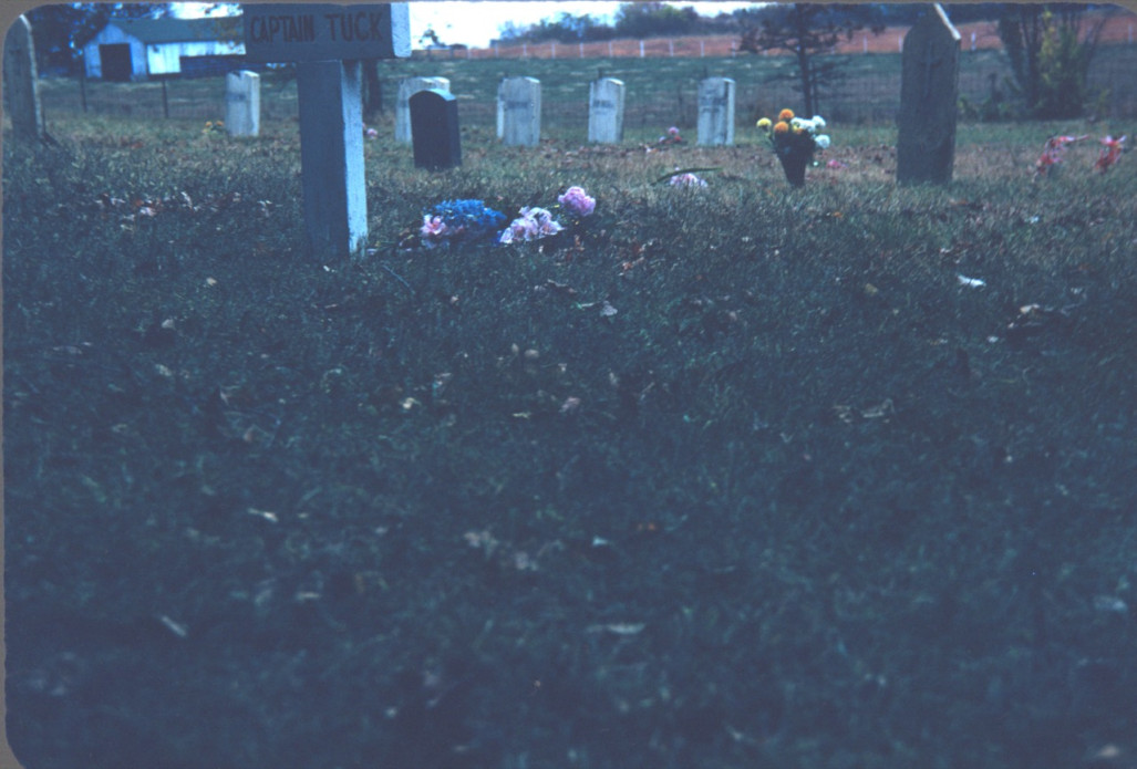 Graveyard with flowers by tombstones Photograph of a graveyard, likely taken around when the funeral of Sarah Winger was filmed.