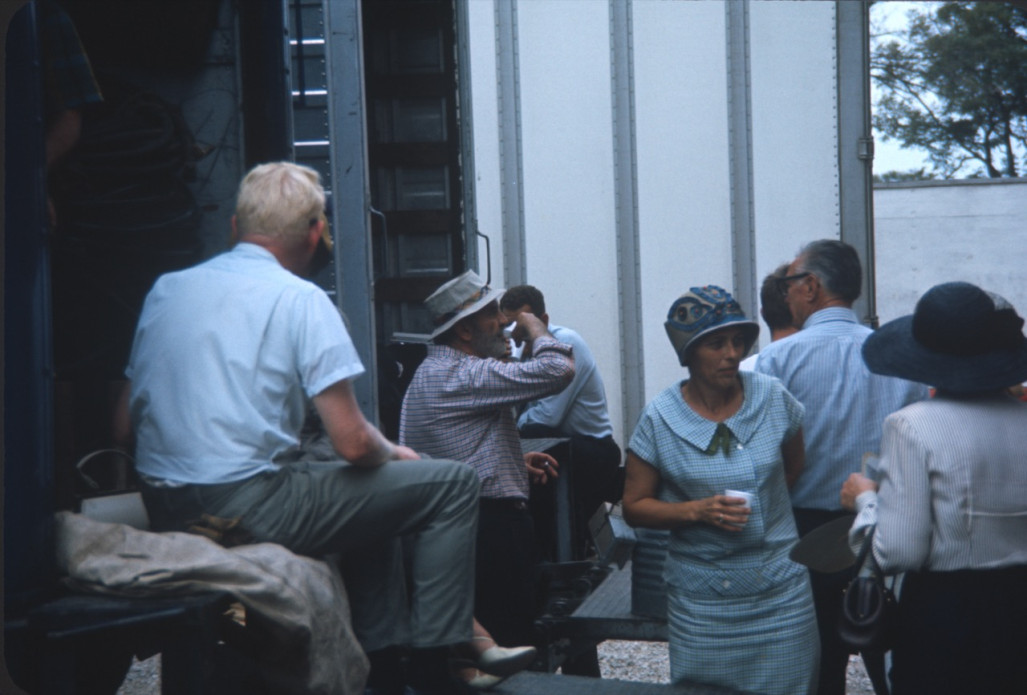 Cast members and production crew taking a break by production trucks.