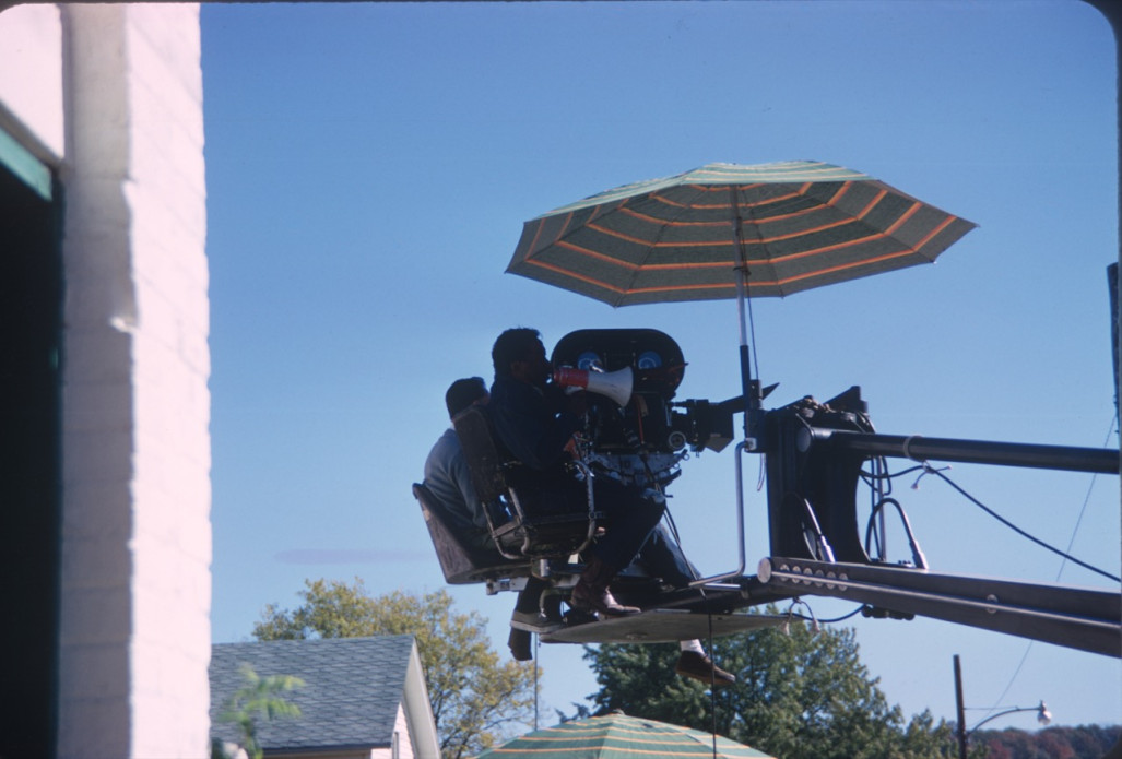 Director Gordon Parks giving direction in megaphone while filming from above.