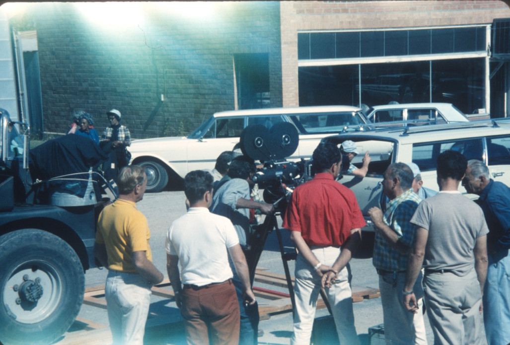 Director Gordon Parks looking through a camera with production crew around him in downtown Fort Scott, Kansas.